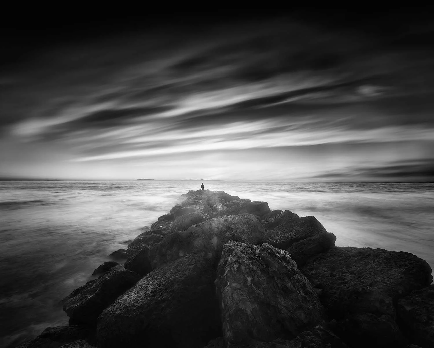 Man sitting on edge of rocky pier